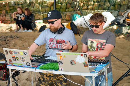 Svetlogorsk, Russia - 08.14.2021 - Disc jockeys playing music, remixing on drum machine midi controller. DJs playing beat sampler with drum pads and samples. Deejays make beats at beach party outsideのeditorial素材