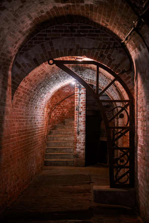 Old brick loft wall in secret military basement. Old wine vault, passageway of mansion. Ancient vintage German fort with dim lighting and brick walls, Kaliningradの写真素材