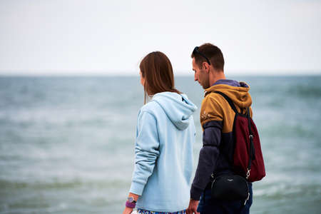 Baltiysk, Russia - 08.01.2021 - Loving couple walking along seashore with shoes in hands. Young man and woman dating by Baltic Sea. Candid couple talking about their romantic relationshipのeditorial素材