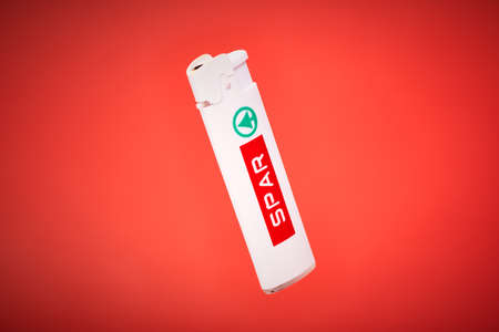 Kaliningrad, Russia - 09.11.2021 - Pocket lighter with SPAR on red background. Plastic lighter for cigarettes, fireworks, candles, campfire. Disposable liquid gas igniter with piezo ignitionのeditorial素材