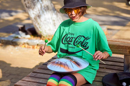 Zelenogradsk, Russia - 07.30.2021 - Street musician girl playing on steel tongue drum. Hank drum...