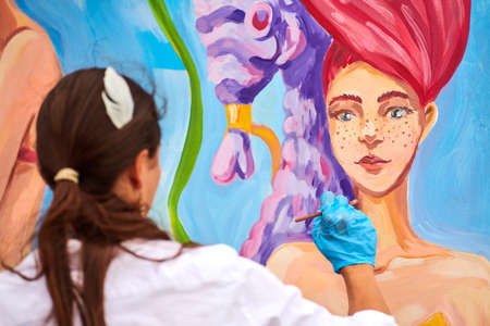 Svetlogorsk, Russia - 08.15.2021 - Female artist painting with brush on wooden canvas board at...