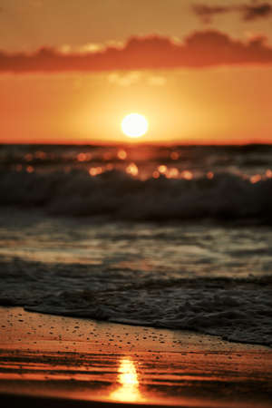 Sunset light reflection on sea sand surface, beautiful yellow sunlight in sea foam. Warm sandy beach at sunset light, atmospheric sunset on seashore, dramatic view to golden sea sandの写真素材