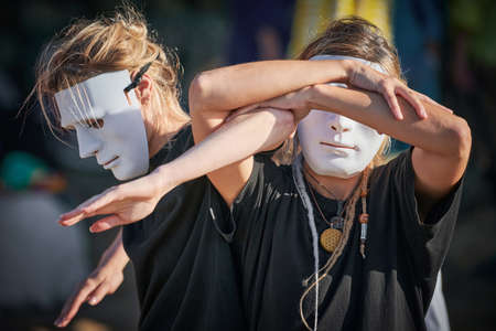 Two women in white theater mask dancing on art theatrical festival. Outdoor dance performance of two...