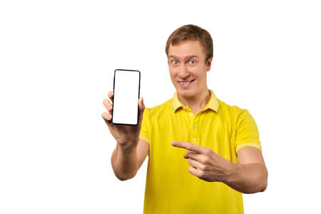 Smiling young guy with smartphone in hand isolated on white background, phone mockup. Funny man in...