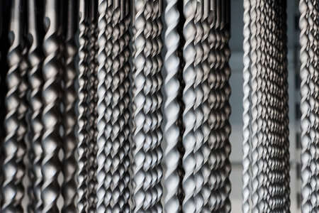 Hammer drill bits in hardware store background, small depth of field. Bunch of drill bits for working with concrete and metal surfaces, construction tool for making round holesの写真素材