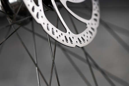 Hydraulic bicycle disk brakes, gray metal disc attached to bike wheel close up, effective popular...