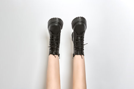 Woman legs in black combat boots on high heel platform with lug soles upside down, white backgroundの写真素材