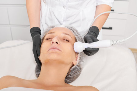 Cosmetologist makes RF lifting for rejuvenation woman face, anti aging cosmetic procedure