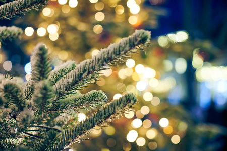 Christmas tree covered snow with yellow garlands lights and bokeh copy space with sparkled bokeh