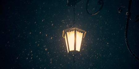 Vintage lamppost with yellow glowing in evening winter snowstorm, copy space on blurred snowflakesの写真素材
