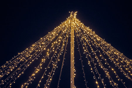 Yellow lights garlands outdoor hanging wires from pillar at night blue sky background
