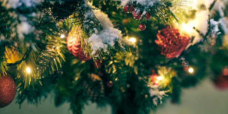 Christmas tree bulbs with yellow garlands covered snow, outdoor xmas tree with decorative red bulbsの写真素材