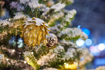 Christmas tree cone bulbs with yellow garlands covered snow, outdoor xmas green tree with conesの写真素材