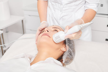 Beautician makes cryotherapy for rejuvenation woman face, anti aging procedure in salon