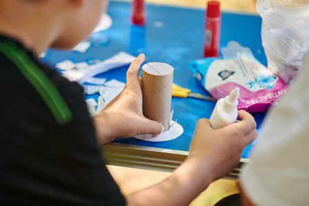 Children paper crafting with parents in outdoor children party, painting stickers and making figures