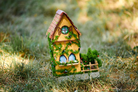 Little dollhouse on front lawn, cute small decorative house on green grass field, copy spaceの写真素材