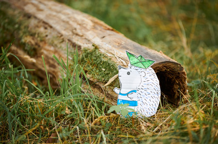 Little hedgehog paper craft with ship on needles on green wood background, cute children craftの写真素材