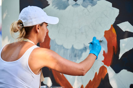 Woman artist hand holds paint brush and draws abstract surreal image on canvasの写真素材