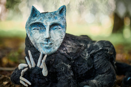 Black cat in human face mask art object outdoor art exhibition in public park weird black creatureの写真素材