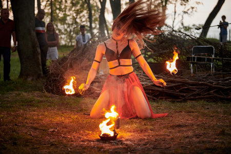 Girl fire dancing performance at outdoor art festival, smooth movements of female artist