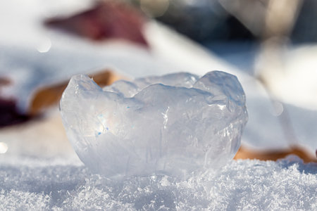A frozen soap bubble has popped and collapsed in on itself as it rests on the snow.の写真素材