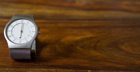 man's wristwatch on a wooden counter showing 6 o'clockの写真素材