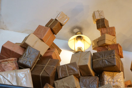 Pile of brown and beige gift boxes with a lamp in the background