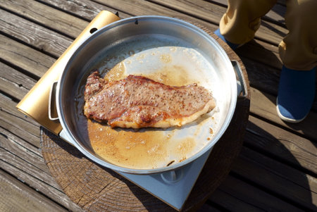 Baking sirloin steaks for camping mealsの写真素材