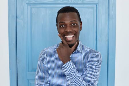 Young and handsome dark-skinned man having fun, grimacing  at office break indoor, looking and showing tongue at the camera. People and lifestyle concept.の写真素材