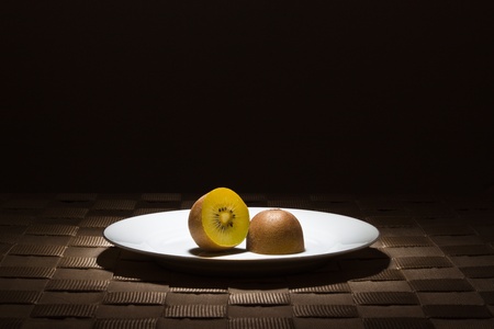 Sliced golden flesh Kiwi on gold rimmed white plate in the spotlightの写真素材