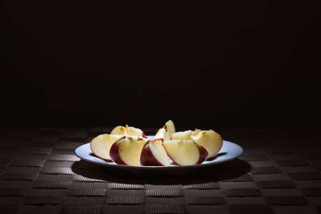 Apple slices on gold rimmed white plate in the spotlightの写真素材
