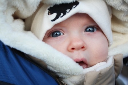 A close up image of a baby in a parka and a tuqueの写真素材