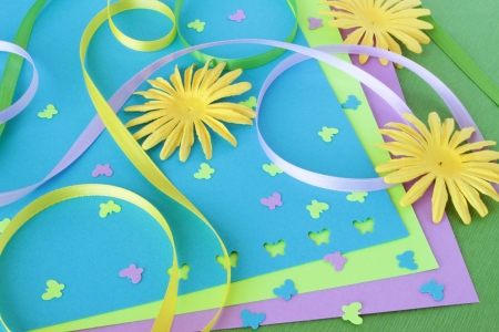 A spring themed collection of card making or scrapbooking supplies, including yellow paper flowers, colorful ribbons, and butterfly shaped confetti.の写真素材