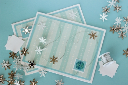 An image of two hand made greeting cards with a winter theme, with card making supplies including snowflake shaped brads and craft wire.の写真素材