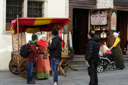 TALLINN, ESTONIA - APRIL 11, 2017: Tourists in Old City. Sellers of almond nuts in national medieval dresses.のeditorial素材