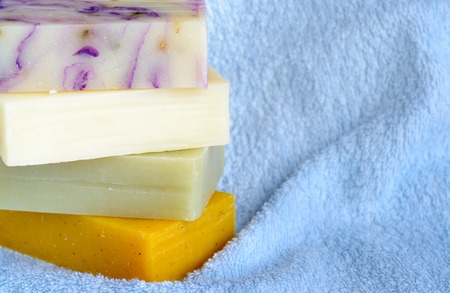 Natural handmade soaps on blue bath towel background.