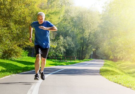 Active middle aged man running in public park