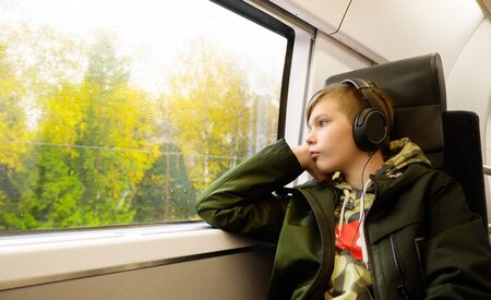 Teenage boy listen music with headphone while traveling by trainの写真素材