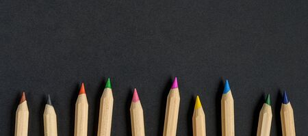 Colored wooden pencils on black paper background. School suppliesの写真素材