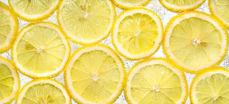 Slices of lemon in water with air bubblesの写真素材