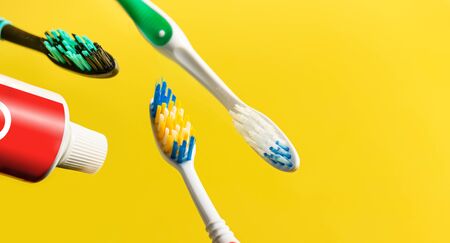 Toothbrushes and toothpaste tube over yellow background. Copy space. Selective focus.