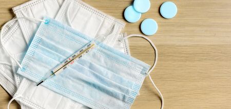 Medical masks, thermometer and pills for protection against coronavirus. Top view on the table background, copy spaceの写真素材