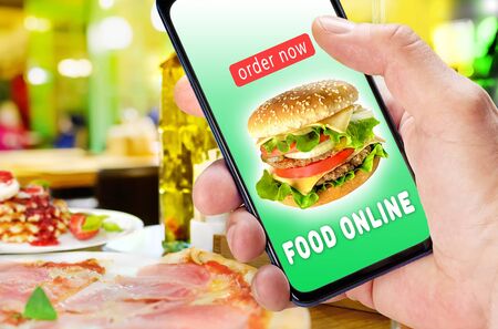 Hand holding phone with app ordering and delivery food over blur restaurant backgroundの写真素材
