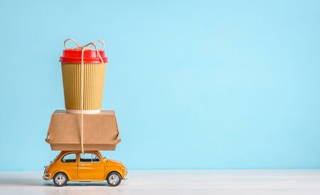 Retro toy car delivering food order on blue background. Copy spaceの写真素材