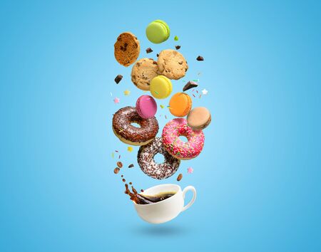 Pastries, confectionery flying over coffee cup with splash. Sweetshop and coffeeshop concept background. Copy space.の写真素材
