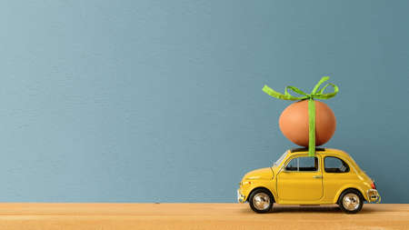 Retro car carrying an easter egg on the roof. Copy space