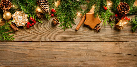 Fir tree branches and christmas decorations with garland on wooden background.の写真素材