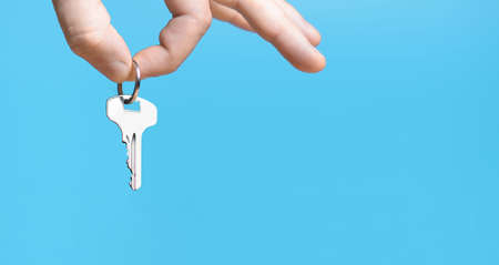 Hand with home key on blue background.