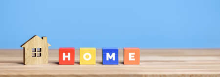 Model House and wooden blocks with word Home on blue background.の写真素材